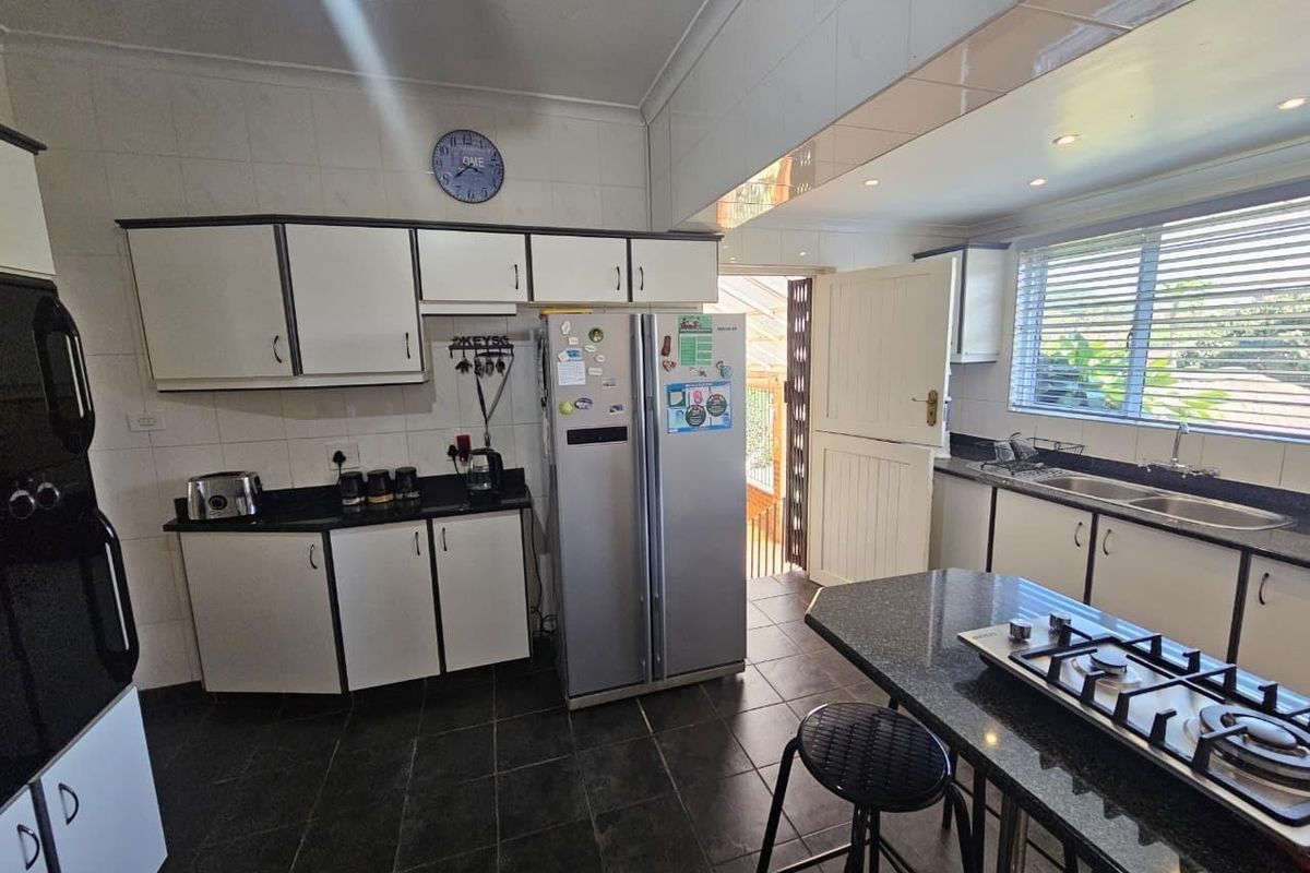 Functional kitchen featuring dark granite countertops, white cabinetry, gas hob, and tiled flooring with direct access to an outdoor area via a dutch door.