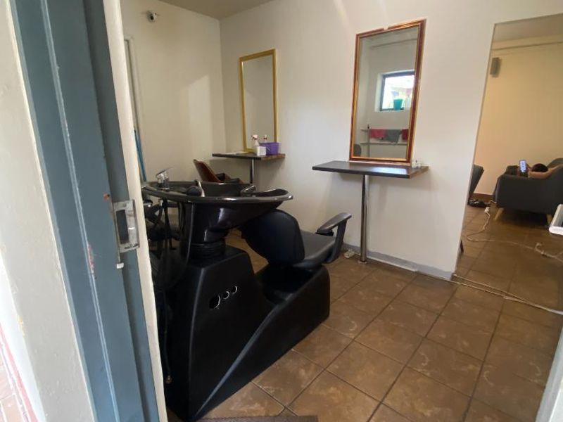 A functional utility space currently configured as a salon area, featuring tiled flooring and wall-mounted mirrors.