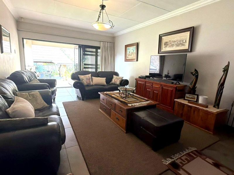 A comfortable living room featuring tiled flooring, decorative cornicing, and large sliding glass doors that provide access to the outdoor area.