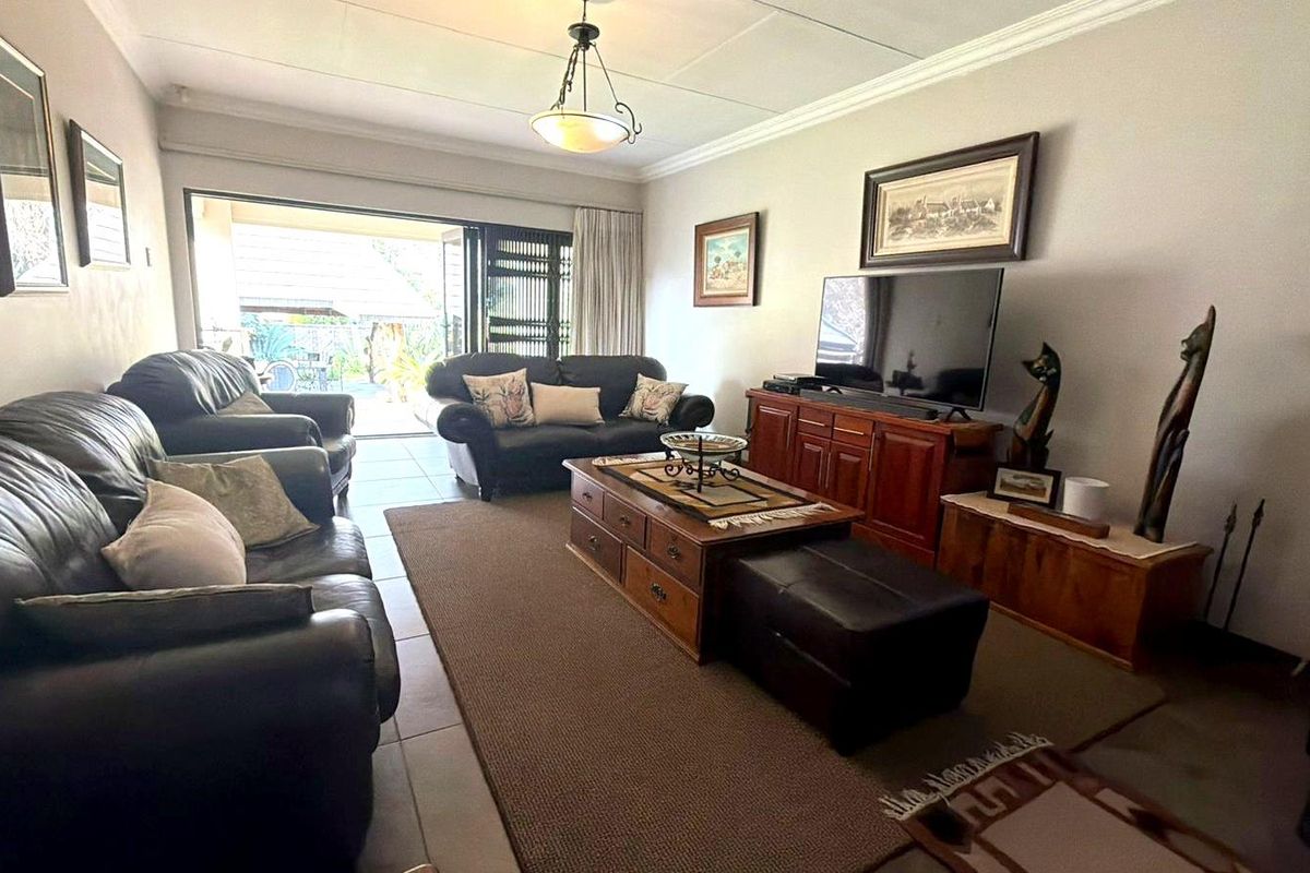 A comfortable living room featuring tiled flooring, decorative cornicing, and large sliding glass doors that provide access to the outdoor area.