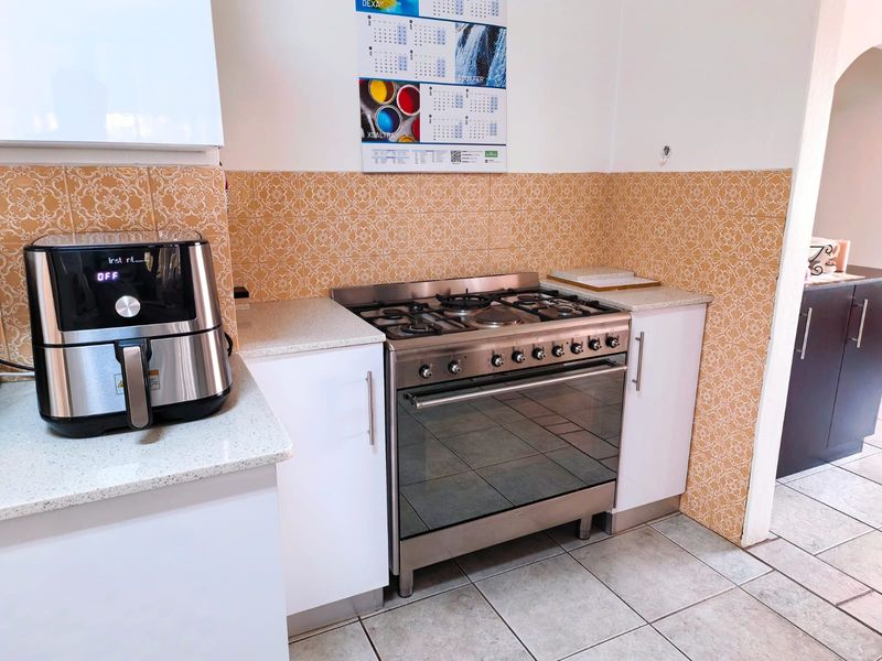 A functional kitchen area featuring a stainless steel gas stove and oven, complemented by patterned tiled backsplash and stone countertops.