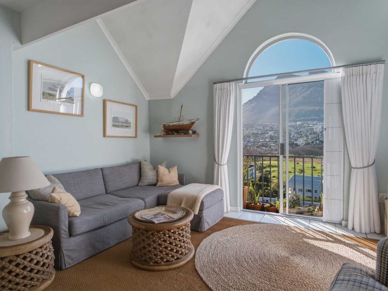 Bright living room featuring a vaulted ceiling, arched window, and sliding glass door leading to a balcony with scenic mountain views.
