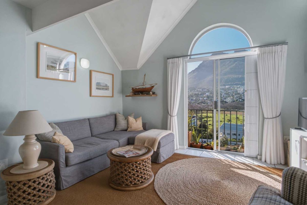 Bright living room featuring a vaulted ceiling, arched window, and sliding glass door leading to a balcony with scenic mountain views.