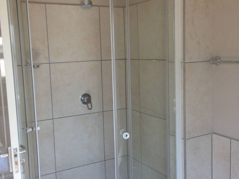 A clean bathroom featuring a curved glass shower enclosure with tiled walls and a mosaic floor finish.