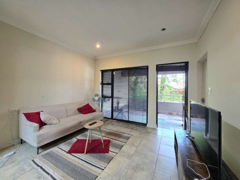A living room featuring tiled flooring, recessed lighting, and a sliding glass door providing direct access to an outdoor balcony area.