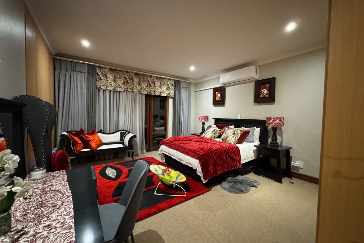 Spacious bedroom featuring neutral carpeting, recessed downlighting, and a wall-mounted air conditioning unit.