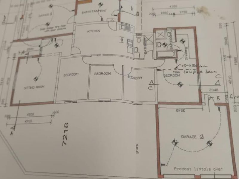 A printed architectural floor plan showing the layout of the house, including bedrooms, bathrooms, kitchen, living areas, and garages.