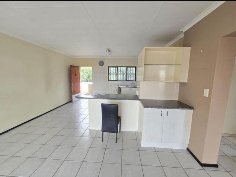 Open plan living and kitchen area featuring tiled flooring, built-in cabinetry, and a breakfast bar, offering a blank canvas for renovation.
