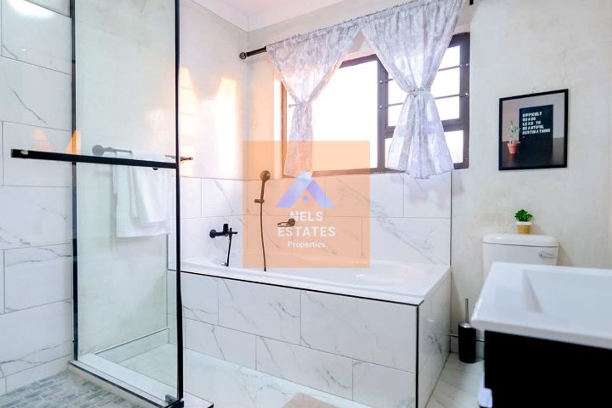 Modern bathroom featuring a glass-enclosed shower, a built-in bathtub with marble-look tiling, and a vanity unit.
