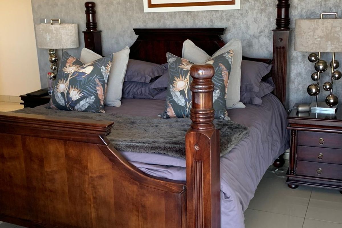 A well-maintained bedroom featuring tiled flooring and a textured feature wall, providing a comfortable and neutral space.