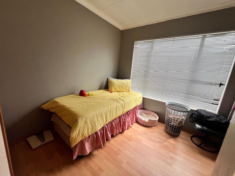 A standard bedroom featuring laminate flooring and large windows fitted with venetian blinds, offering a neutral base for interior design.