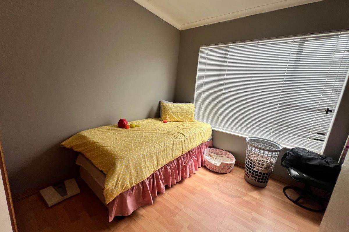 A standard bedroom featuring laminate flooring and large windows fitted with venetian blinds, offering a neutral base for interior design.