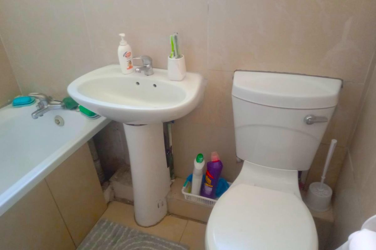 A functional bathroom featuring a pedestal sink, a standard toilet, and a bathtub with tiled wall finishes.