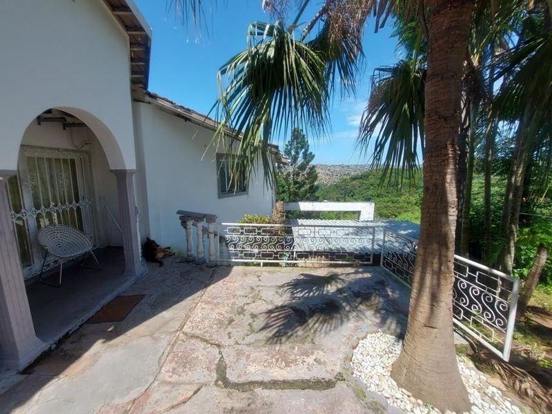 An outdoor patio area featuring stone paving, wrought iron railings, and an arched entrance, offering elevated views of the surrounding landscape.
