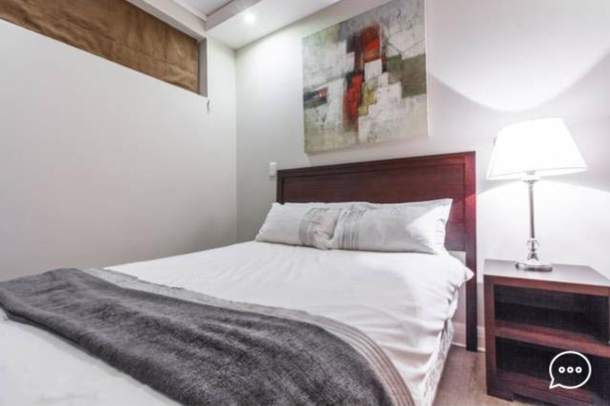 A well-maintained bedroom featuring modern laminate flooring and recessed ceiling lighting, providing a clean and comfortable living space.