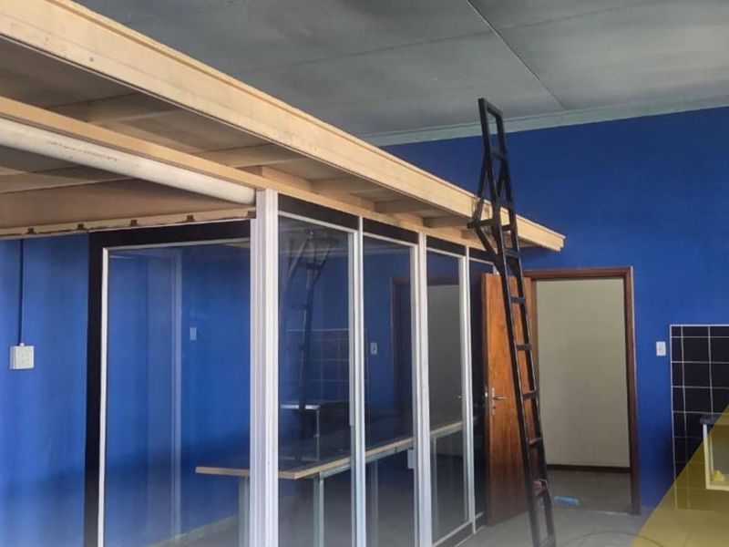 An open-plan office space featuring a mezzanine level, glass partitions, and tiled flooring, suitable for a versatile business environment.