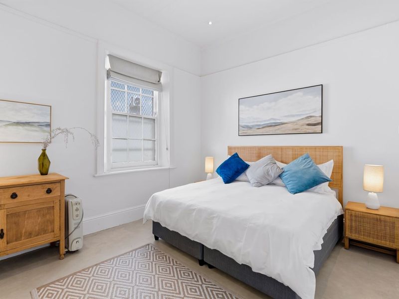 A bright and well-maintained bedroom featuring classic sash windows, crisp white walls, and elegant cornicing, creating a clean and inviting living space.