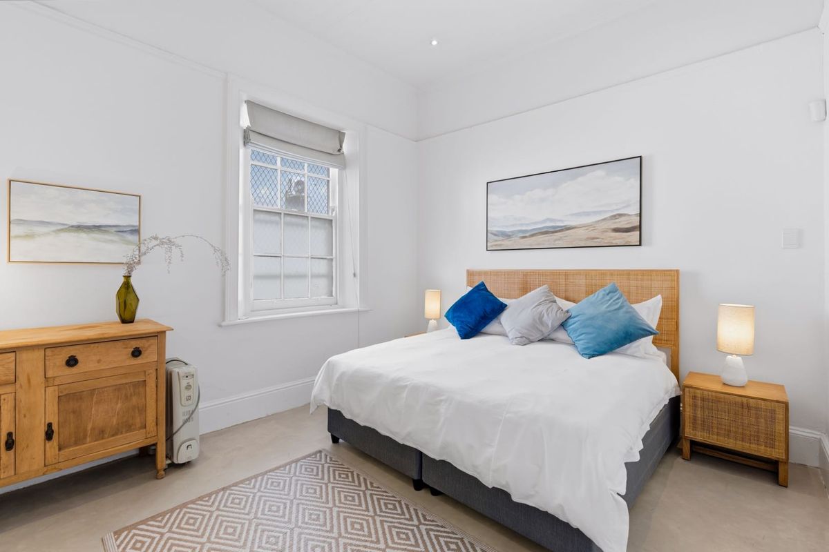 A bright and well-maintained bedroom featuring classic sash windows, crisp white walls, and elegant cornicing, creating a clean and inviting living space.