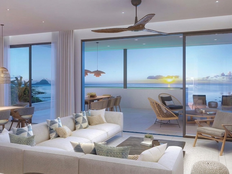 Spacious open-plan living and dining area featuring large sliding glass doors that open onto a balcony with scenic ocean views.