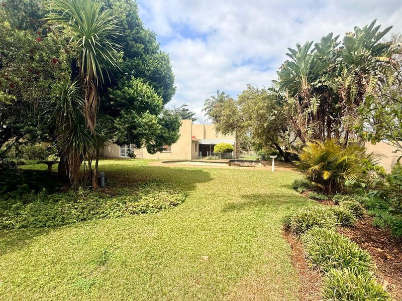 A spacious backyard featuring a well-maintained lawn, mature landscaping, and a swimming pool, offering a private outdoor retreat.