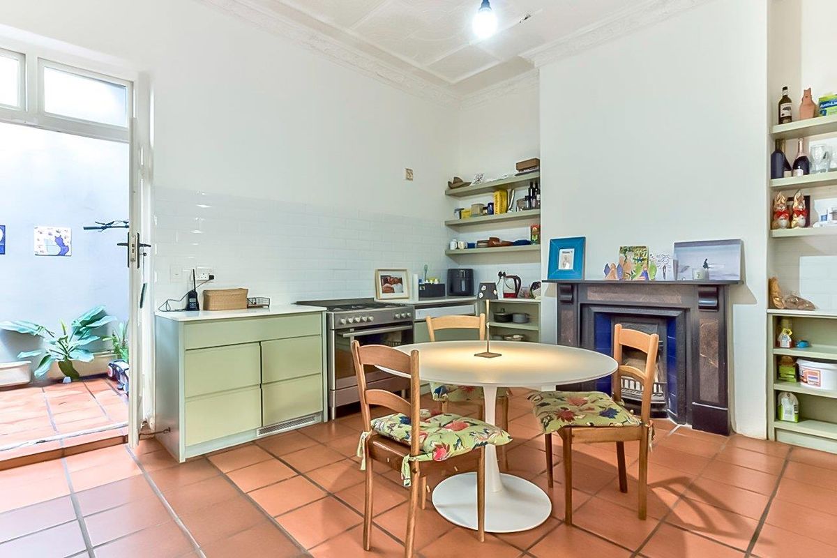 A characterful kitchen featuring terracotta flooring, a built-in fireplace, subway tile backsplash, and direct access to an outdoor patio area.