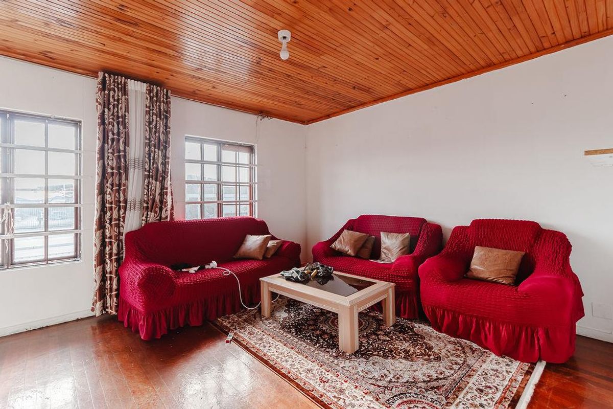 A living room featuring hardwood flooring and a distinctive timber tongue and groove ceiling with grid pane windows.