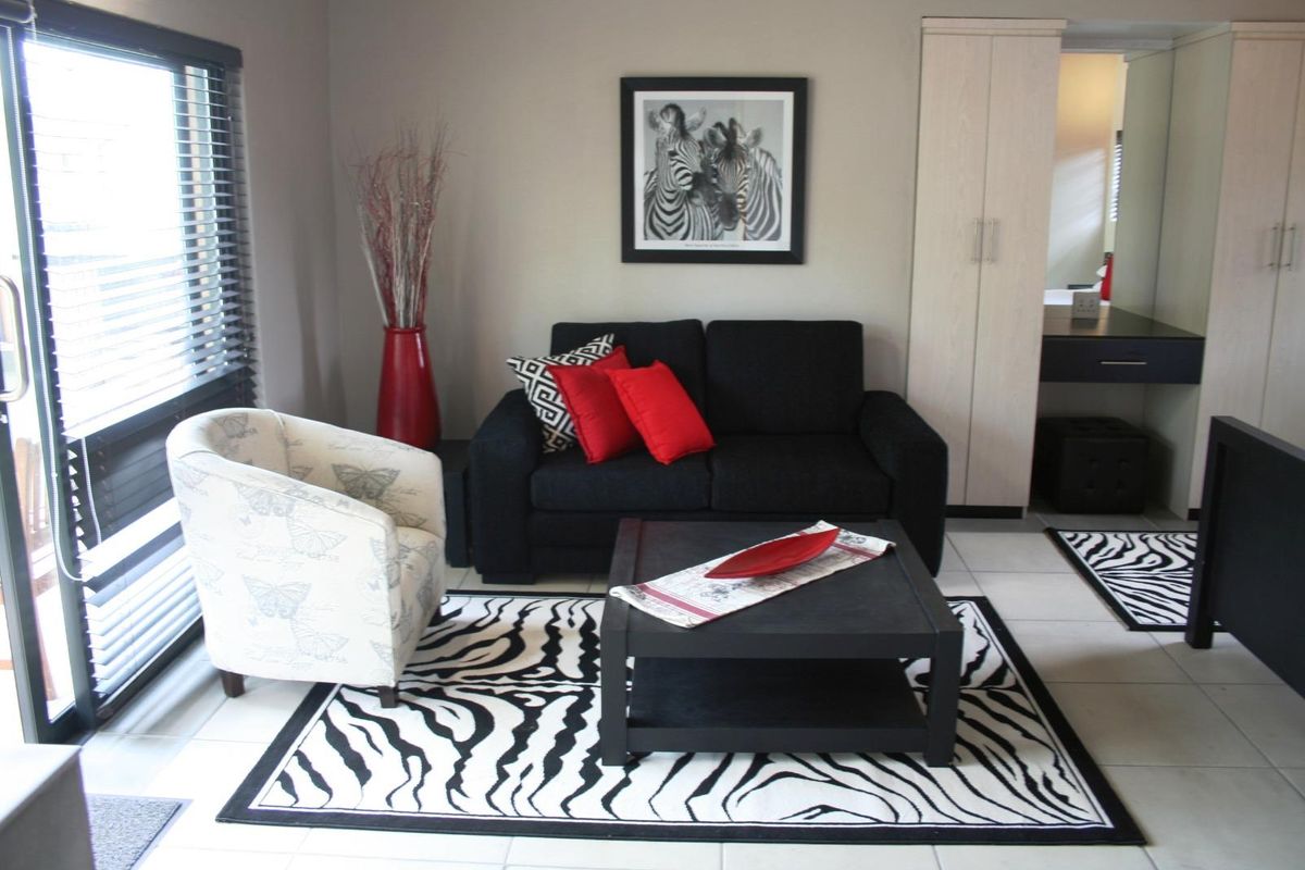 A well-maintained living area featuring tiled flooring, built-in cabinetry, and large windows with fitted blinds, offering a clean and functional space.