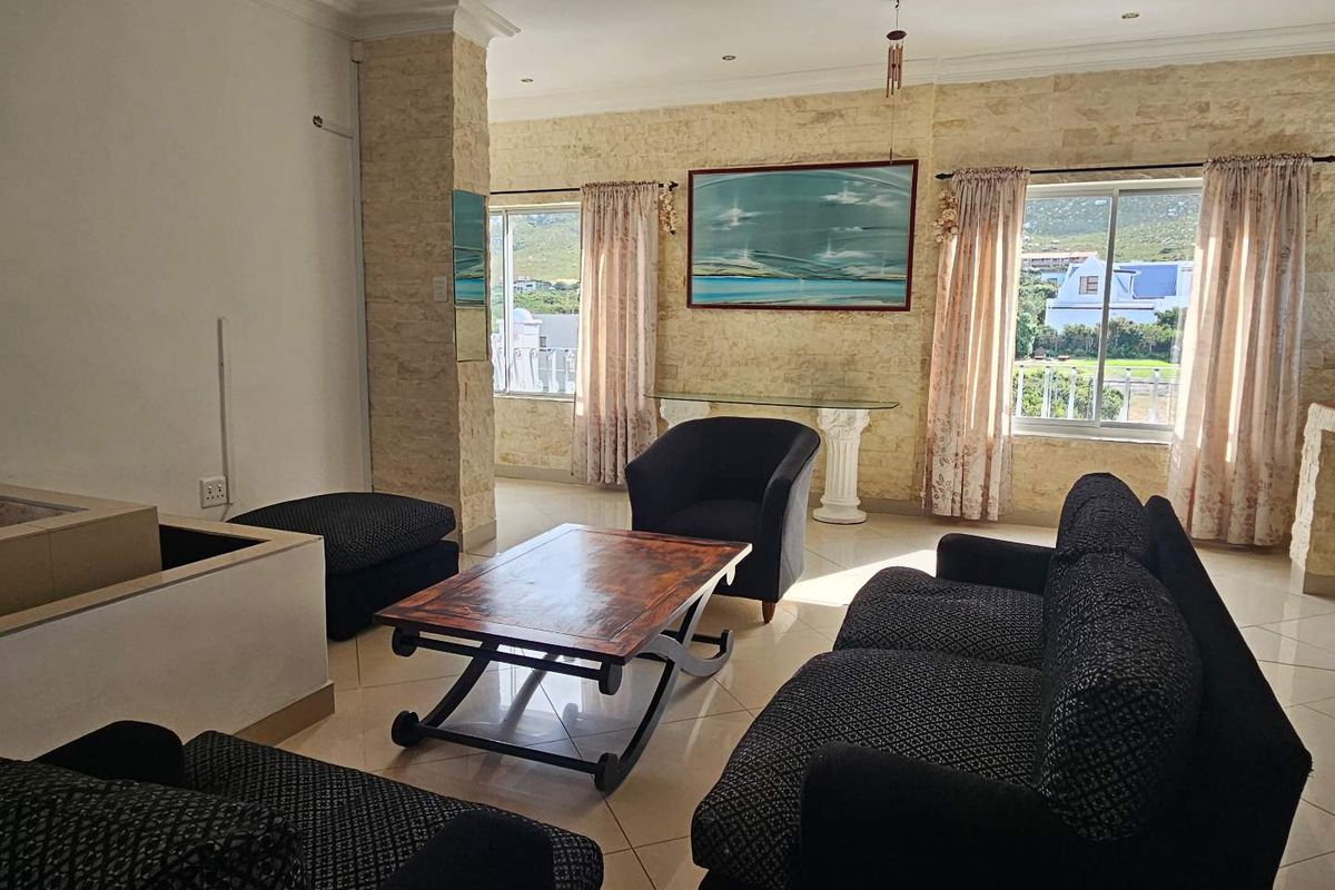 A spacious living room featuring stone-clad accent walls, tiled flooring, and large windows that provide natural light and views.
