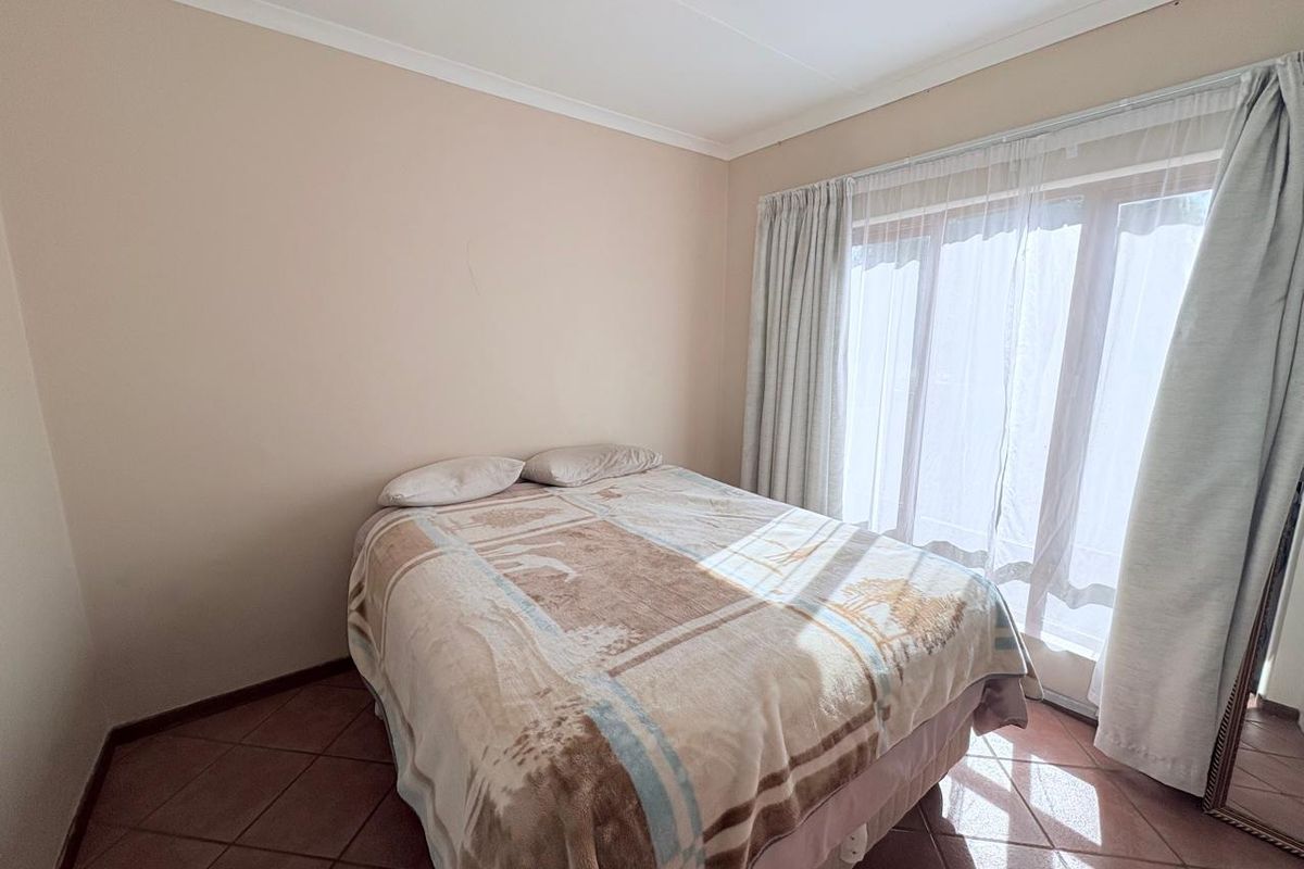 A bedroom featuring tiled flooring and large sliding glass doors that provide natural light and access to the exterior.