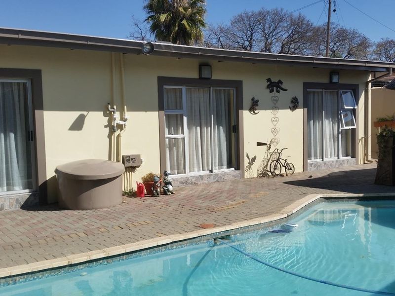 Exterior view of the apartment featuring a swimming pool and paved deck area with direct access via sliding glass doors.
