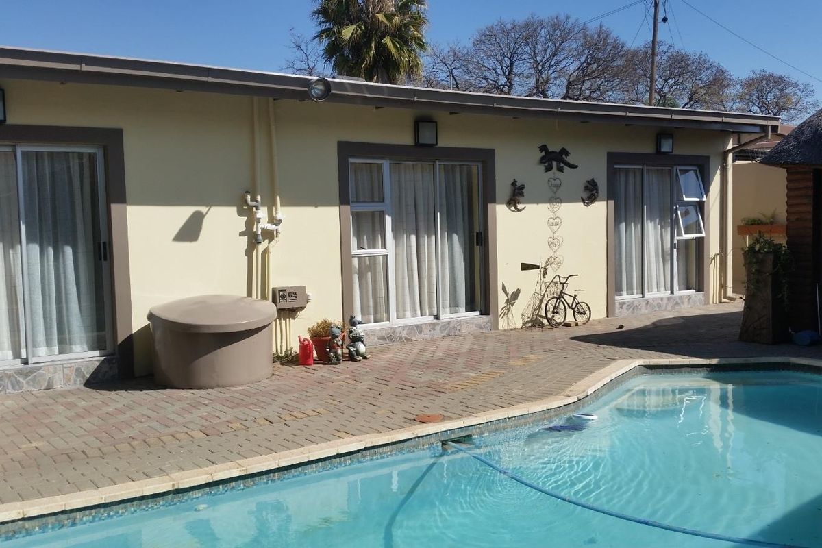 Exterior view of the apartment featuring a swimming pool and paved deck area with direct access via sliding glass doors.