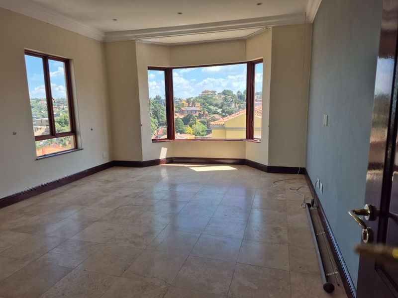 Spacious living area featuring large bay windows with scenic views, tiled flooring, and neutral wall finishes, offering a bright and open atmosphere.