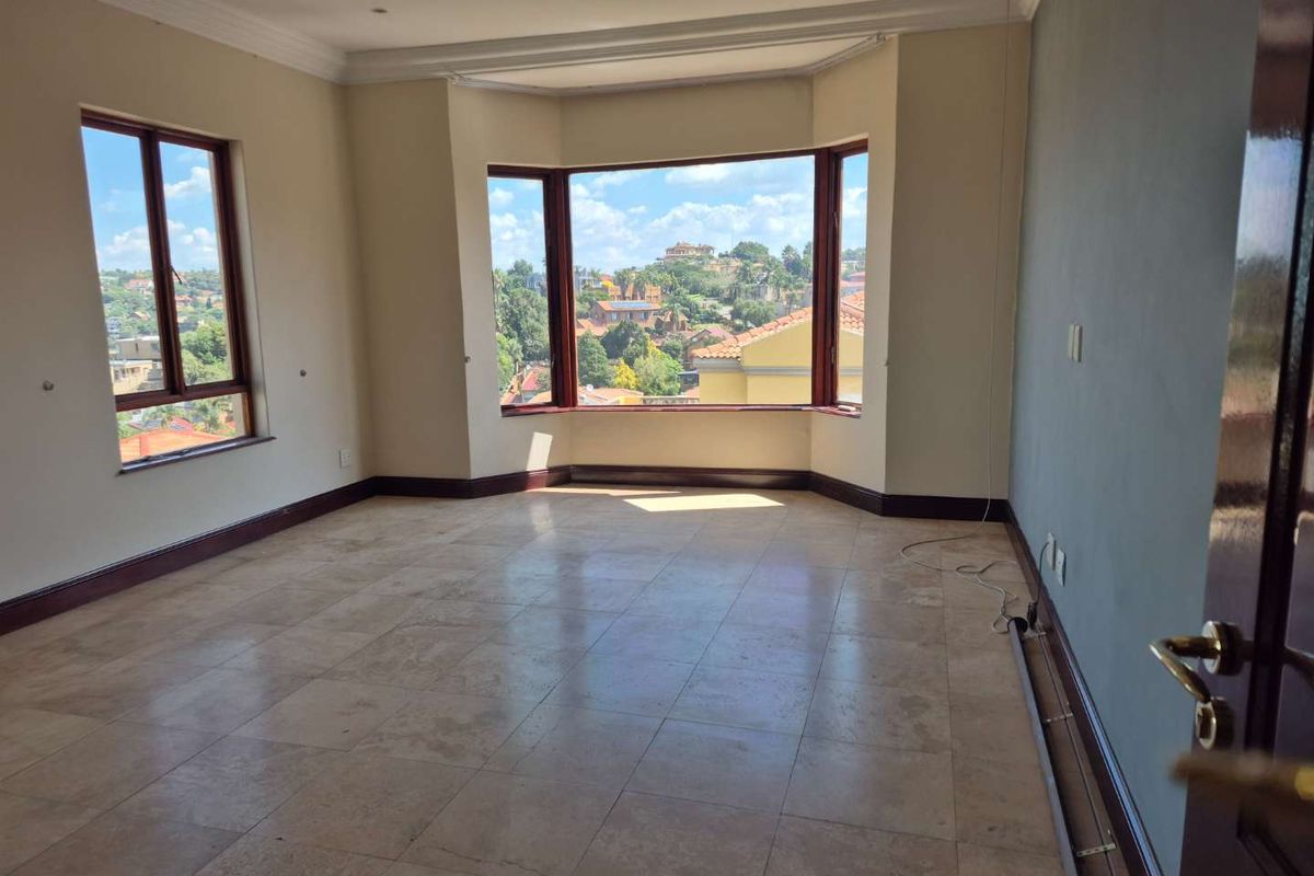 Spacious living area featuring large bay windows with scenic views, tiled flooring, and neutral wall finishes, offering a bright and open atmosphere.