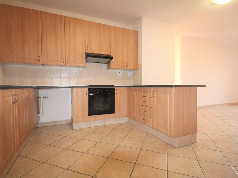 A functional kitchen featuring light wood-finish cabinetry, built-in oven, extractor fan, and tiled flooring, offering a clean and neutral space for culinary activities.