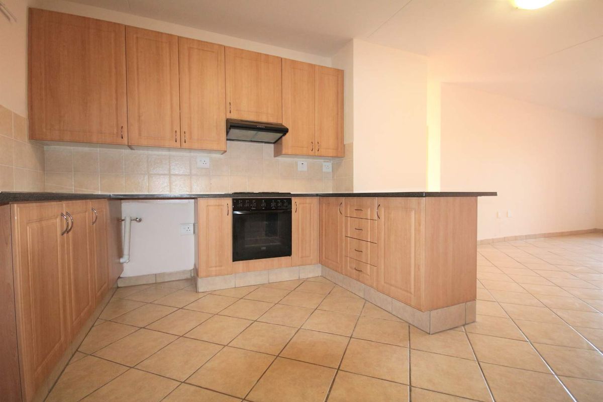 A functional kitchen featuring light wood-finish cabinetry, built-in oven, extractor fan, and tiled flooring, offering a clean and neutral space for culinary activities.
