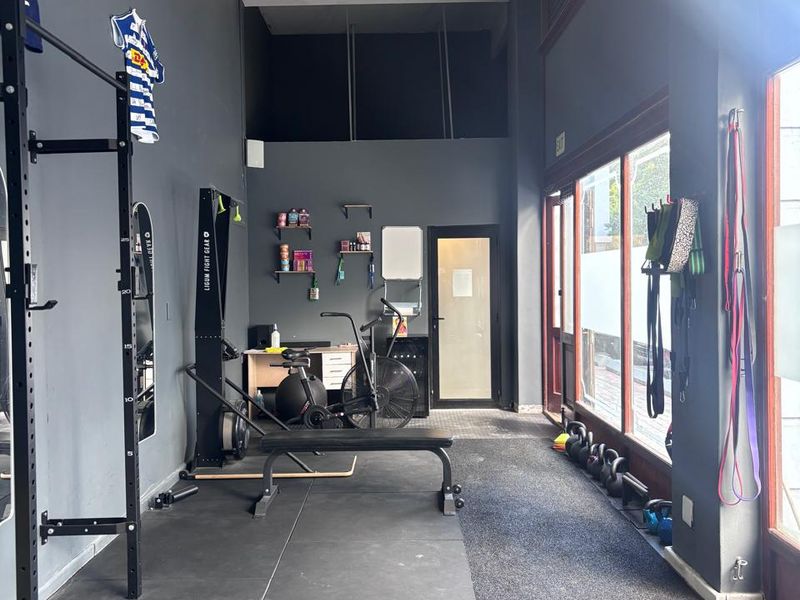 A functional gym space featuring durable rubber flooring, large windows providing natural light, and an exposed structural beam in a modern industrial setting.