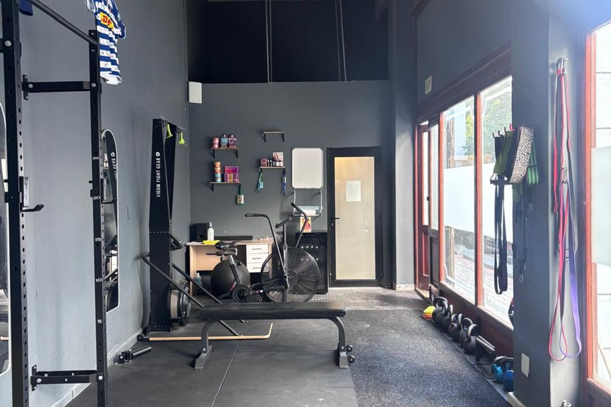 A functional gym space featuring durable rubber flooring, large windows providing natural light, and an exposed structural beam in a modern industrial setting.