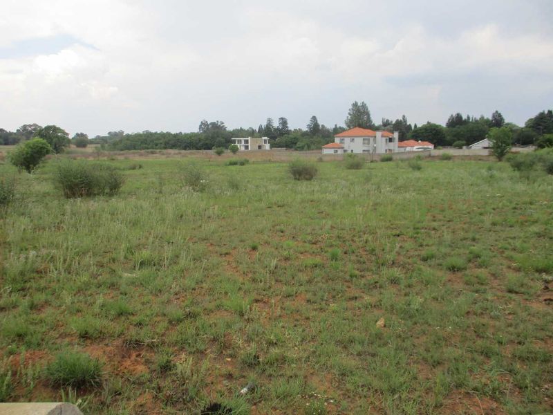 A view of a vacant residential plot featuring natural grassland and surrounding neighborhood development.