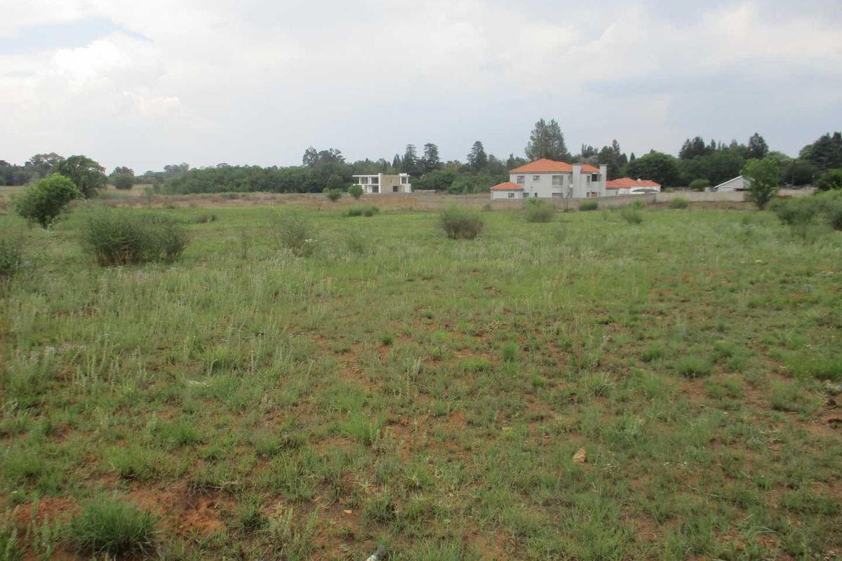 A view of a vacant residential plot featuring natural grassland and surrounding neighborhood development.