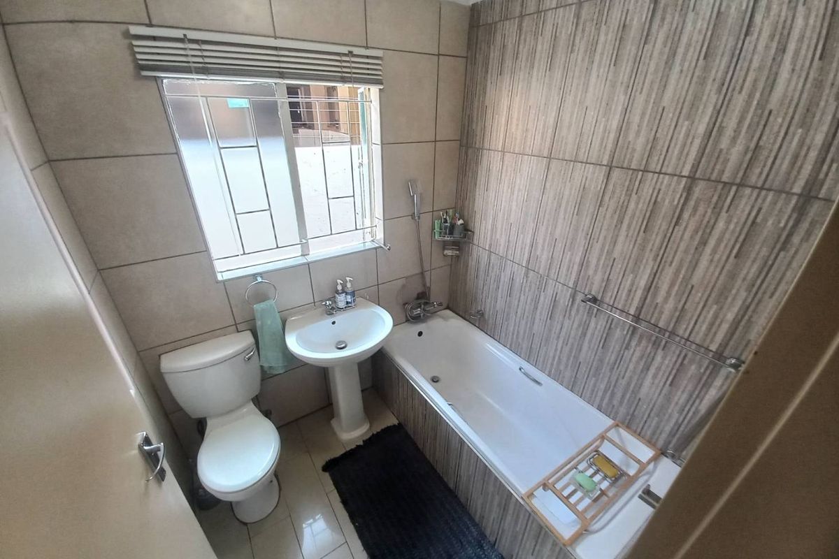 A compact, well-maintained bathroom featuring a pedestal basin, a standard toilet, and a bathtub with tiled wall finishes.