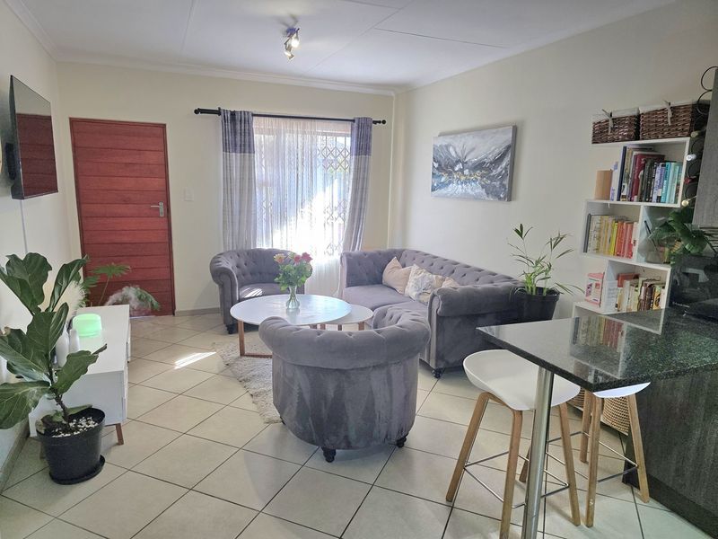 Open plan living area featuring tiled flooring, a granite breakfast bar, and a secure entrance door with natural light.