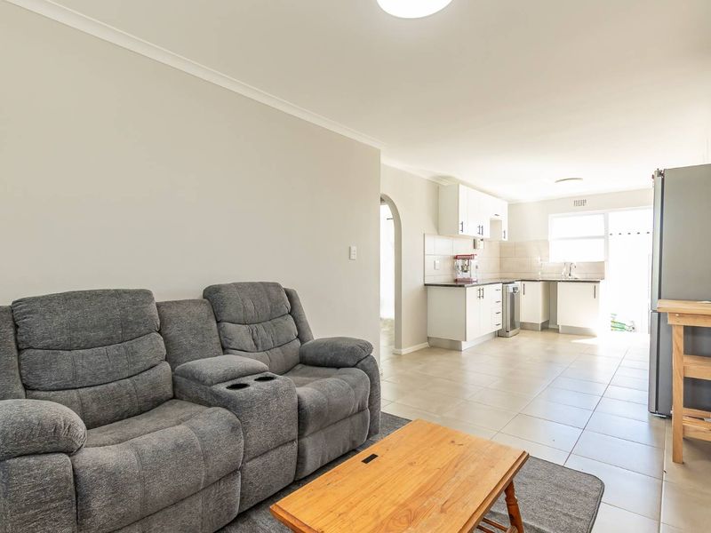 Open-plan living area featuring tiled flooring and a functional kitchen with built-in cabinetry, seamlessly connected to the main living space.