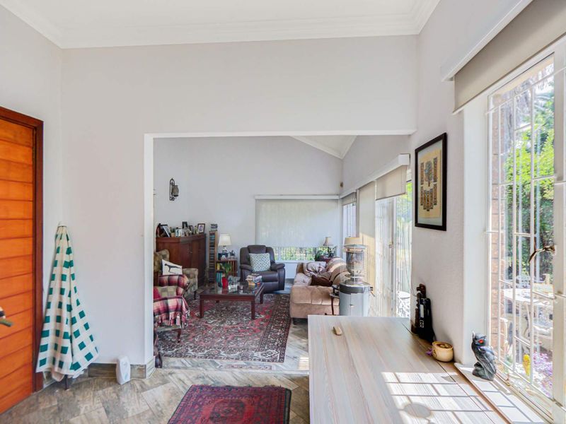 A bright living area featuring tiled flooring, large windows with security bars, and direct access to the outdoor space.