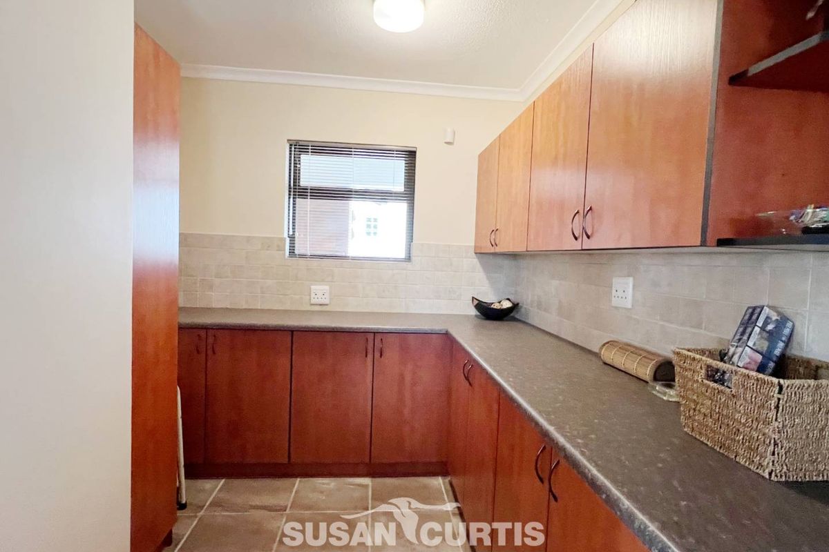 A functional kitchen featuring wood-tone cabinetry, stone-look countertops, tiled backsplash, and tiled flooring, providing ample storage and workspace.