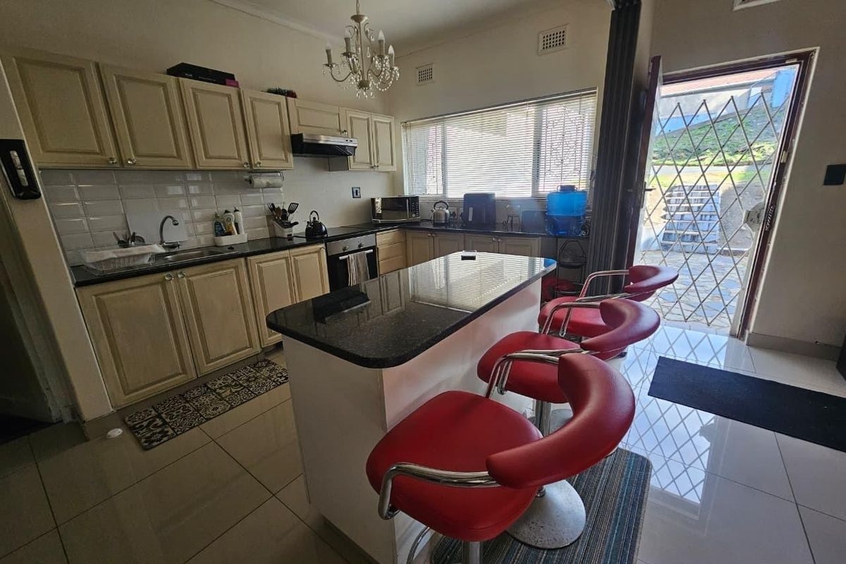 Functional kitchen featuring granite countertops, built-in cabinetry, a central island, and direct access to the exterior through a security gate.