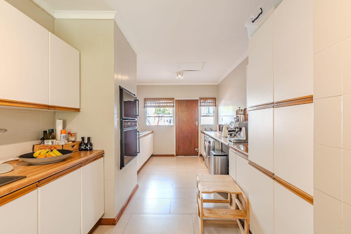 A functional kitchen featuring built-in cabinetry, integrated oven, and tiled flooring, providing ample storage and workspace for daily culinary activities.