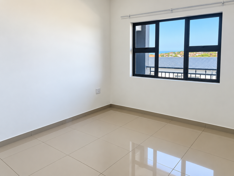 A bright, empty bedroom featuring neutral tiled flooring, clean white walls, and a large window with views of the surrounding area.