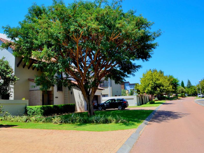 Front exterior view of the property featuring a paved driveway, well-maintained garden, and established tree, showcasing the street-facing facade and entrance.