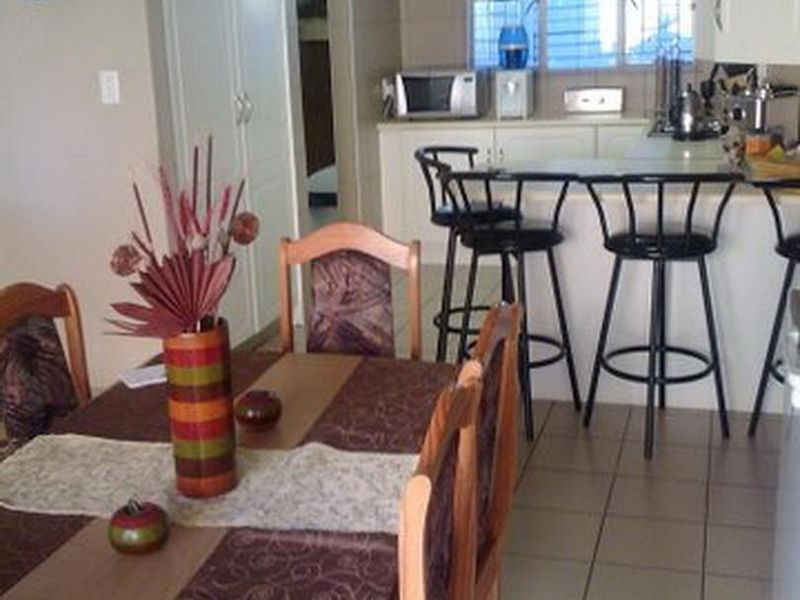 Open plan kitchen and dining area featuring tiled flooring, built-in cabinetry, and a breakfast bar counter.