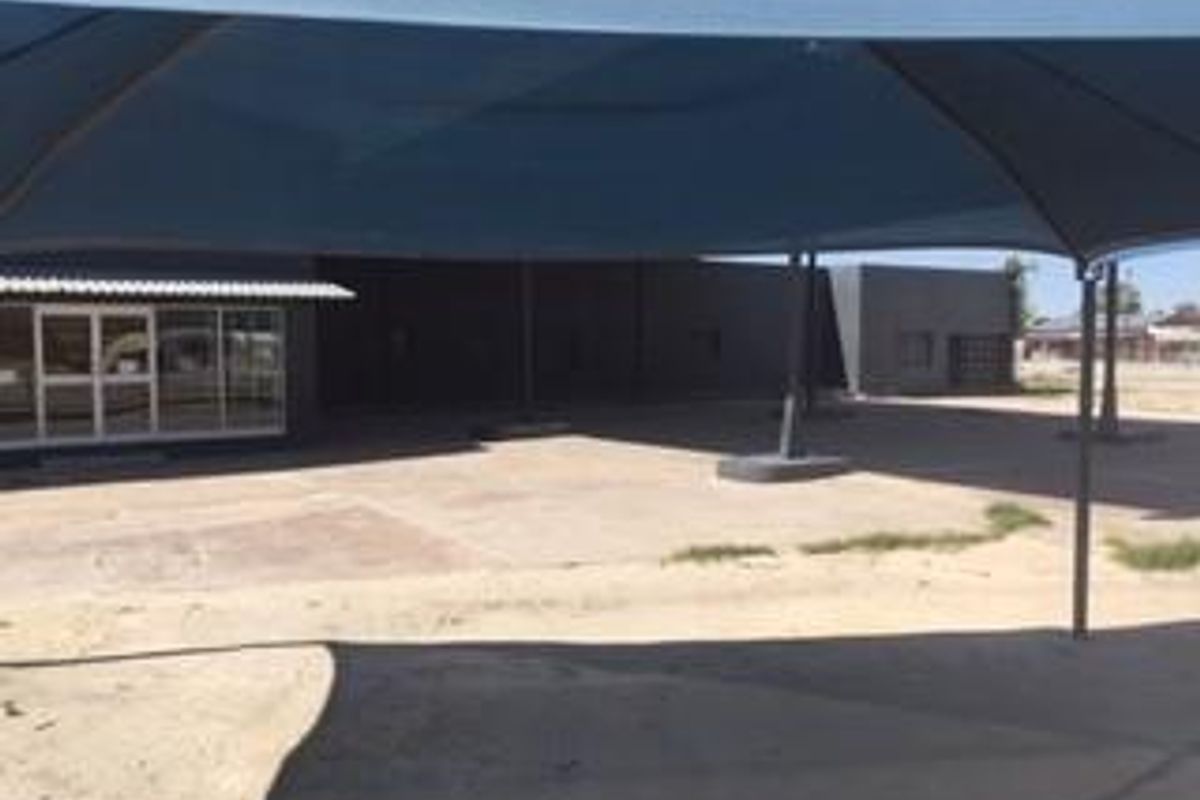 Exterior view of the property featuring a large paved courtyard area covered by a shade sail structure.